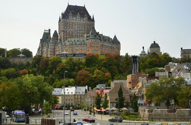 Photo de Québec avec le Château Frontenac surplombant la Basse-Ville et un boulevard où circulent des voitures et des autobus.
